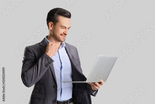 Handsome businessman with laptop on light background