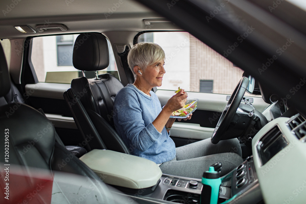 © Davor - Senior woman eating healthy meal in car while parked