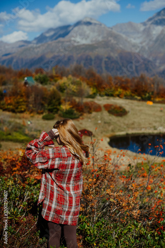 A young woman standing against a stunning mountain backdrop, enjoying the beauty of nature and fresh air.
