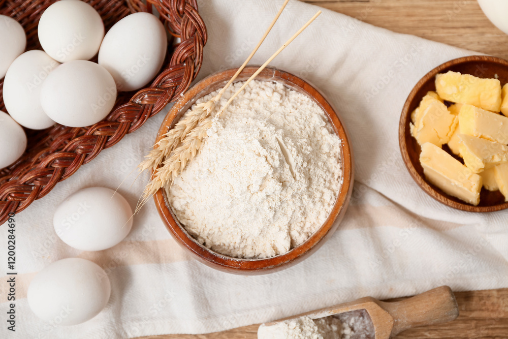 Bowl of flour with scoop, eggs and butter for preparing dough on wooden background Bowl of flour with scoop, eggs and butter for preparing dough on wooden background