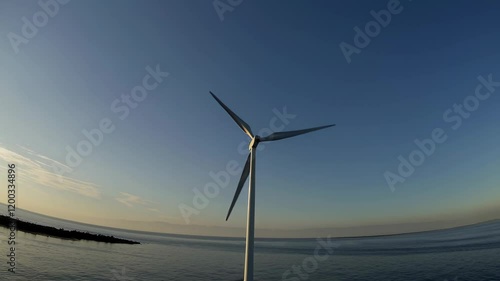 Wallpaper Mural Wind turbine near the coastline under a serene blue sky during sunset, symbolizing sustainable energy Torontodigital.ca
