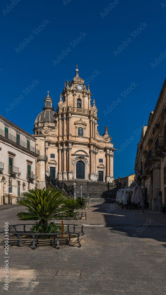 Obraz premium The central square of Ragusa Ibla with the majestic Duomo di San Giorgio. A stunning blend of Baroque architecture and Sicilian charm, capturing the essence of this UNESCO World Heritage site.