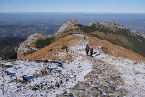 Scenery of autumn Tatras Mountains with silhouettes of hiking people. Giewont Peak on background. Czerwone Wierchy range from around Kasprowy Wierch Peak, Tatras Mountains, Poland.  