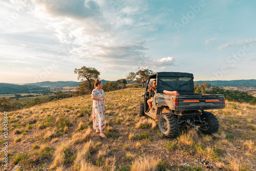 Man and woman chatting on hilltop with off-road farm buggy