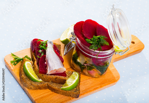 Pickled poutassou in homemade marinade of olive oil and lime juice with spices, onion and beet photo