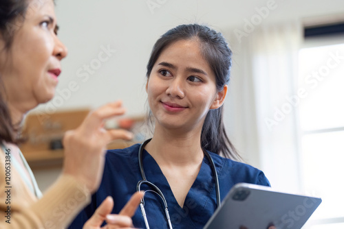 Caregiver engaging in conversation with elderly patient while using a tablet photo