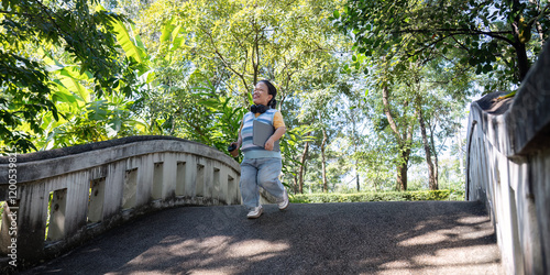 Wallpaper Mural Joyful child with achondroplasia running on a bridge in a lush green park Torontodigital.ca