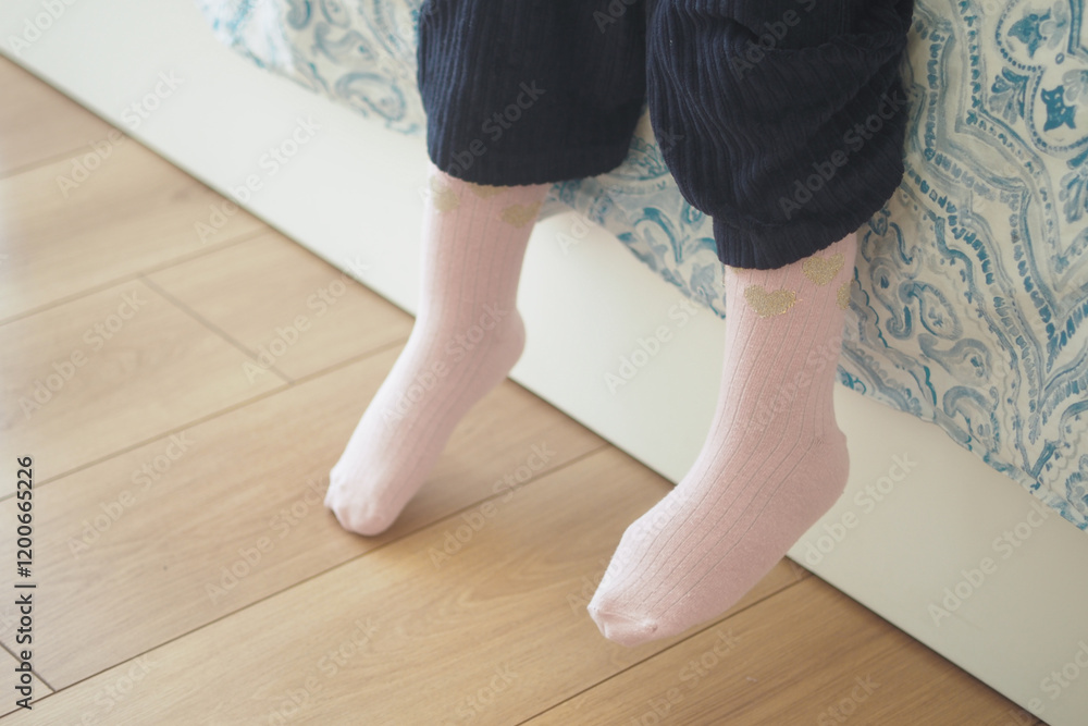 Cute and Cozy Pink Socks Playfully Hanging Off the Side of the Bedside Cute and Cozy Pink Socks Playfully Hanging Off the Side of the Bedside