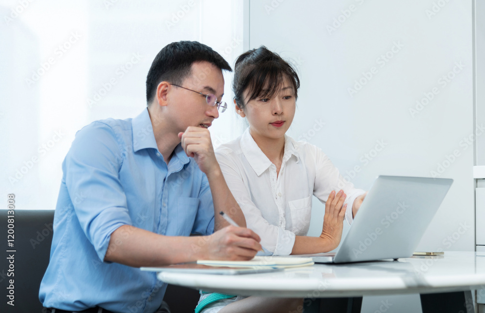 Two asian businesspeople working together in the office while using laptop Two asian businesspeople working together in the office while using laptop