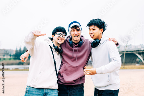 Three cheerful multi-ethnic male teenagers are enjoying and having fun together in a park, symbolizing friendship, and youthful joy photo