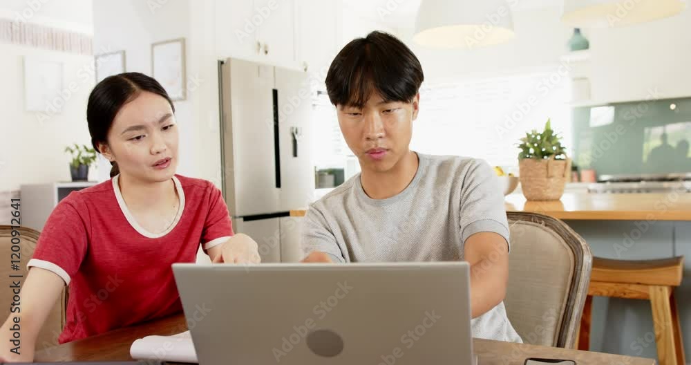 Working from home, Asian brother and sister using laptop and tablet in kitchen Working from home, Asian brother and sister using laptop and tablet in kitchen