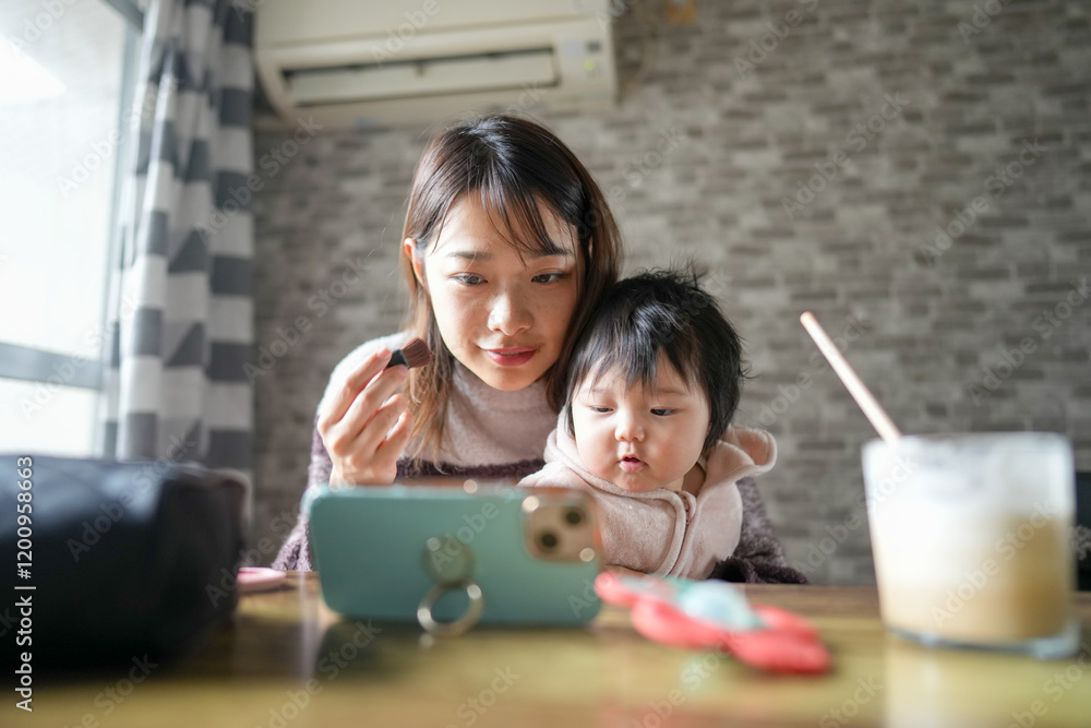 A Japanese mother in her 20s and a 6-month-old baby girl are in the room. She is putting on makeup while looking at her smartphone. A Japanese mother in her 20s and a 6-month-old baby girl are in the room. She is putting on makeup while looking at her smartphone.