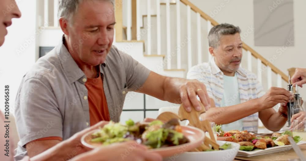 Senior friends enjoying meal together, serving salad and chatting at table