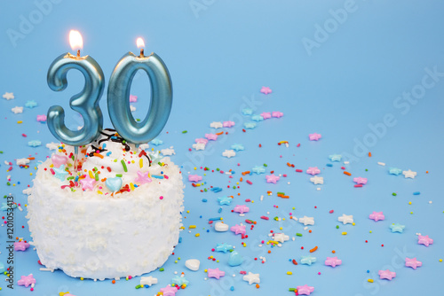Canvas Print White coconut birthday cake on blue background with burning candles and many colorful sprinkles