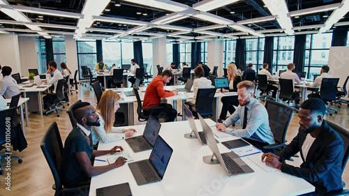 Busy modern office environment with employees collaborating and working at desks in a high-rise building