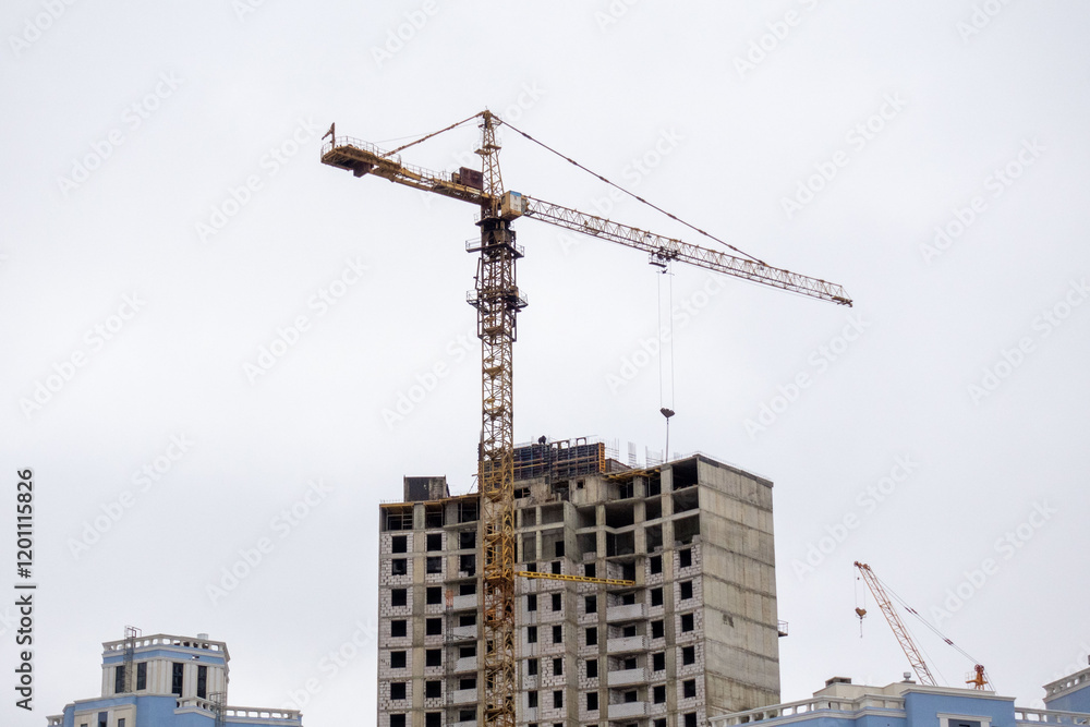 A crane is lifting a large object in front of a building A crane is lifting a large object in front of a building