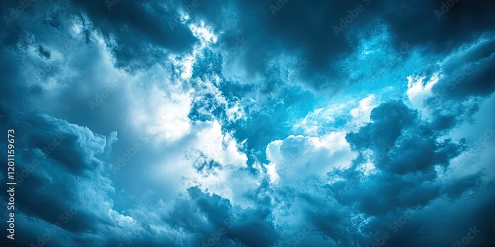Obraz premium Dramatic sky with deep blue tones and varying gray clouds creating an atmospheric backdrop, with bright highlights peeking through.