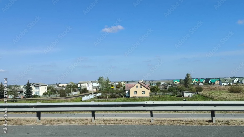 Obraz premium the car is in motion, the view from the window. Autumn landscape, road, residential buildings in rural areas, view from the car window