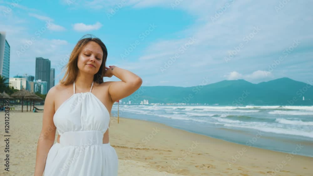 Female walking barefoot on sandy beach, white sundress flowing, vibrant ocean waves and urban skyline framing serene coastal scene Female walking barefoot on sandy beach, white sundress flowing, vibrant ocean waves and urban skyline framing serene coastal scene
