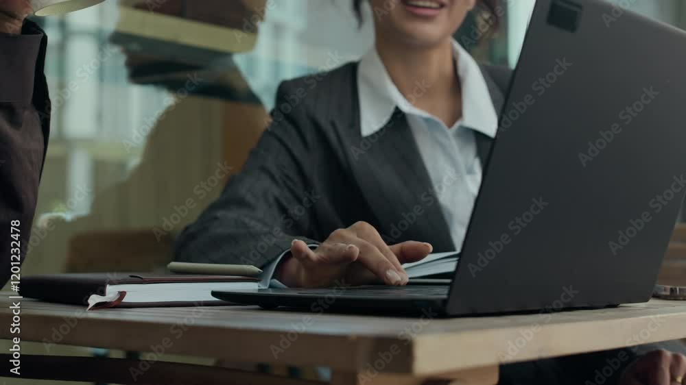 Close-up shot of young businesswoman using touchpad on laptop, while sitting with her friend at table in outdoor cafe during coffee break Close-up shot of young businesswoman using touchpad on laptop, while sitting with her friend at table in outdoor cafe during coffee break