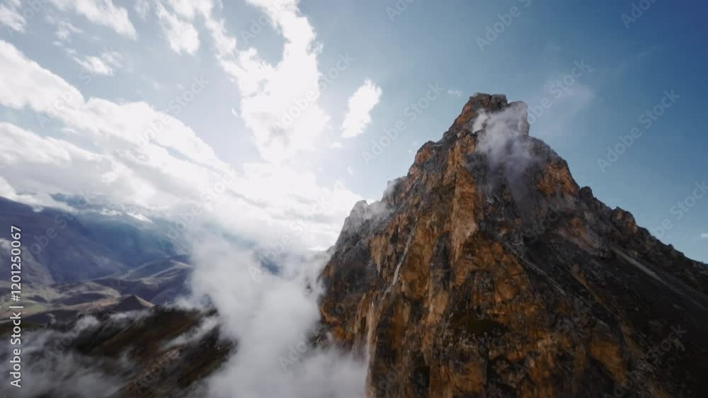 Aerial view of majestic mountains shrouded in low clouds, haze and fog, with impressive rock formations somewhere in the Alps or the Caucasus Aerial view of majestic mountains shrouded in low clouds, haze and fog, with impressive rock formations somewhere in the Alps or the Caucasus