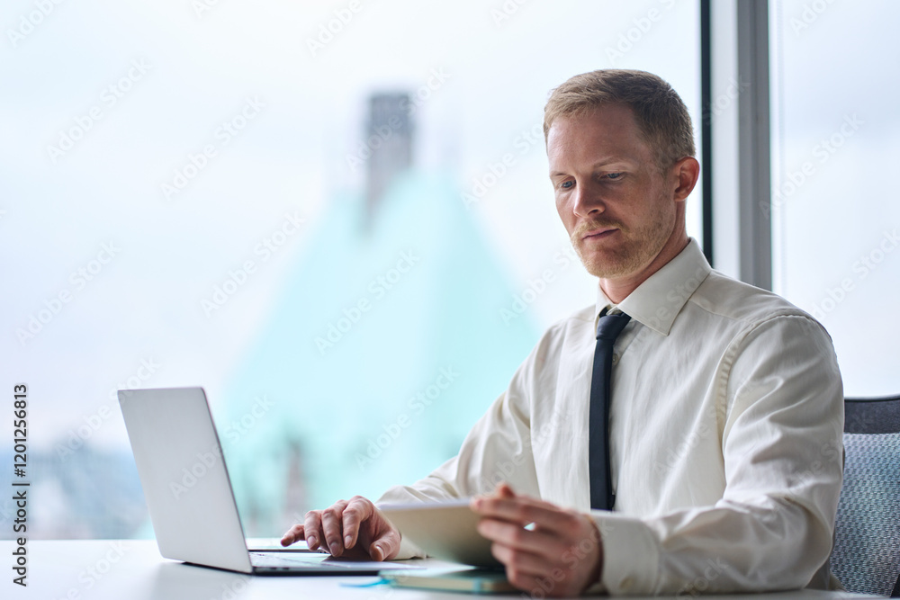 Young busy professional business man executive working on laptop checking notebook in office. Serious corporate bank manager, male ceo, company leader using computer planning project goals at work. Young busy professional business man executive working on laptop checking notebook in office. Serious corporate bank manager, male ceo, company leader using computer planning project goals at work.