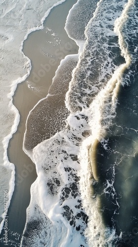 Waves crashing on sandy beach creating foam and ripples during sunset or sunr...