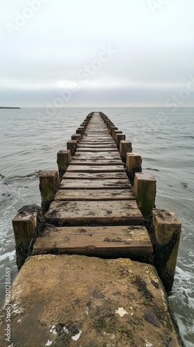Scenic wooden pier extending into tranquil ocean under clear blue sky