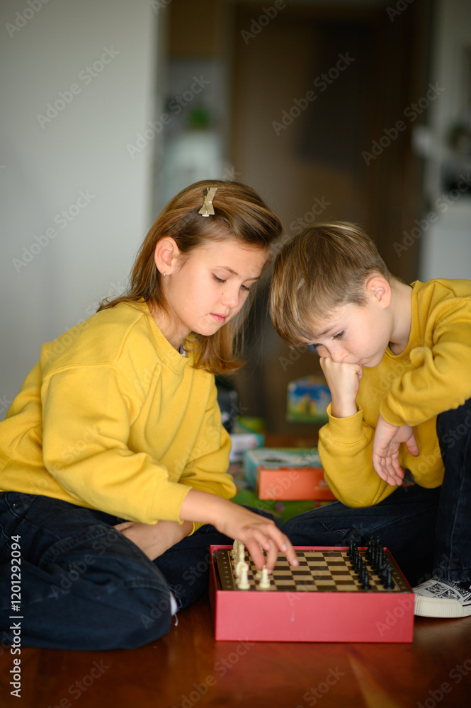 Naklejka premium A boy and a girl play chess together, focused and engaged in the game. The scene reflects concentration and friendly competition, showcasing the fun of strategic thinking and mental challenge.