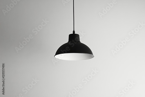 Elegant black pendant lamp hanging against a simple gray background in a mode...
