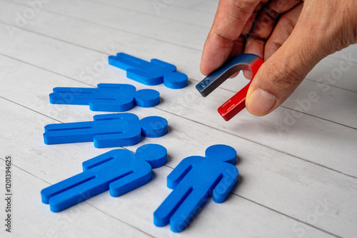Obraz na płótnie Hand holding a magnet attracts a blue figures