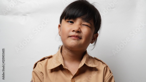 Portrait of an Asian girl with a white background wearing a scout uniform and tied hair smiling while winking.
