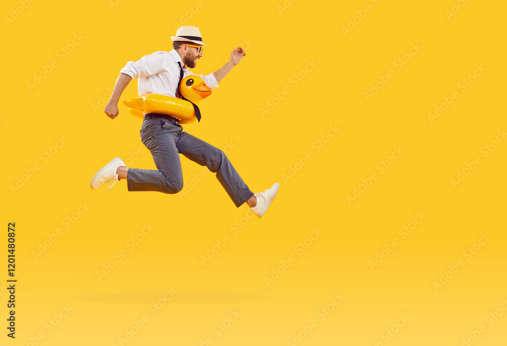 Happy man in office wear with rubber inflatable duck ring jumping for summer dream holiday. Leisure and recreation, travelling, takes break from work, to engage happy activity fun, yellow background Happy man in office wear with rubber inflatable duck ring jumping for summer dream holiday. Leisure and recreation, travelling, takes break from work, to engage happy activity fun, yellow background