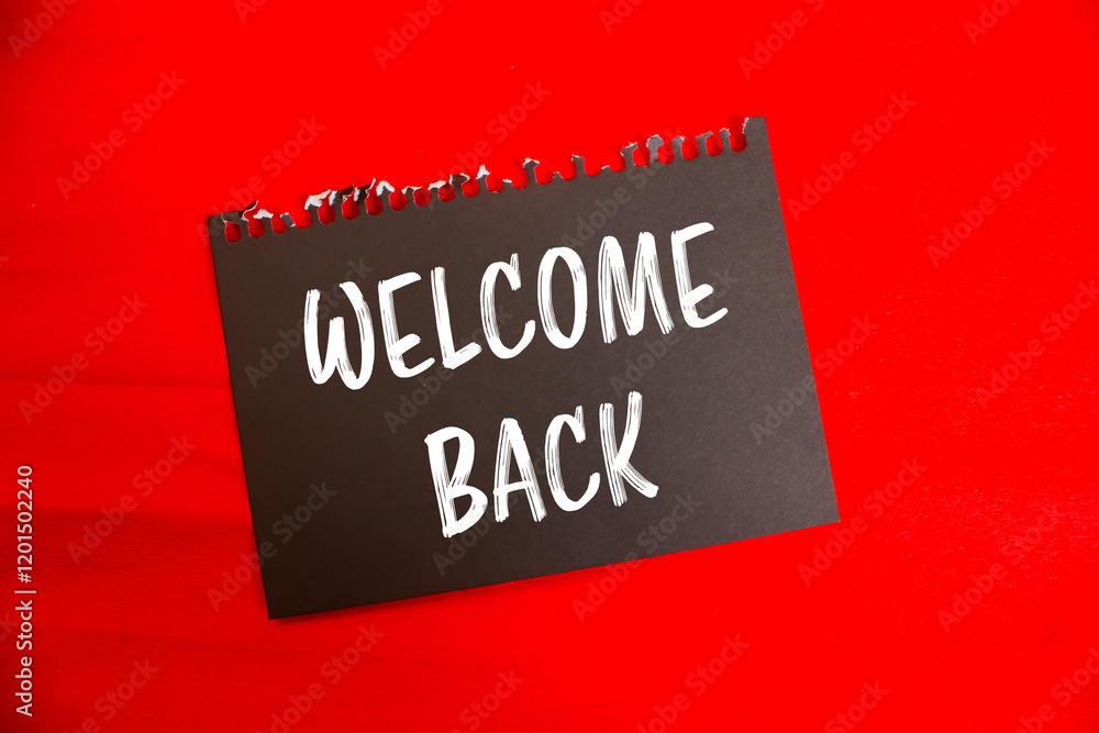 Welcome back message written on black paper with red background. Conceptual welcome back symbol. Copy space. Welcome back message written on black paper with red background. Conceptual welcome back symbol. Copy space.