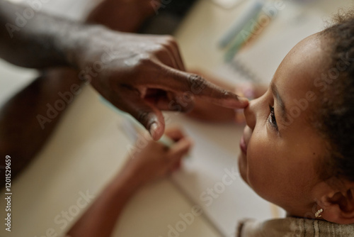 Side view of fathers finger touching small nose of cute little girl expressing love and affection for daughter while studying at home, copy space