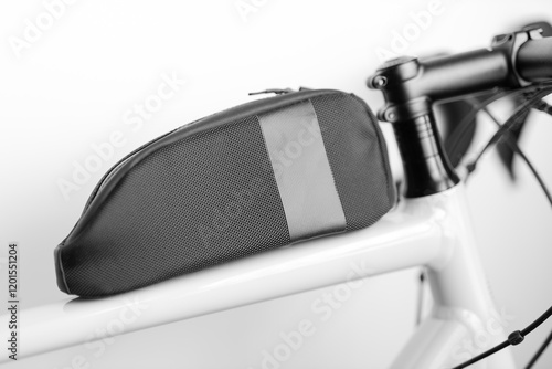 A black and white image of a bicycle with a black bag on the handlebars. The bag is made of mesh and has a zipper photo