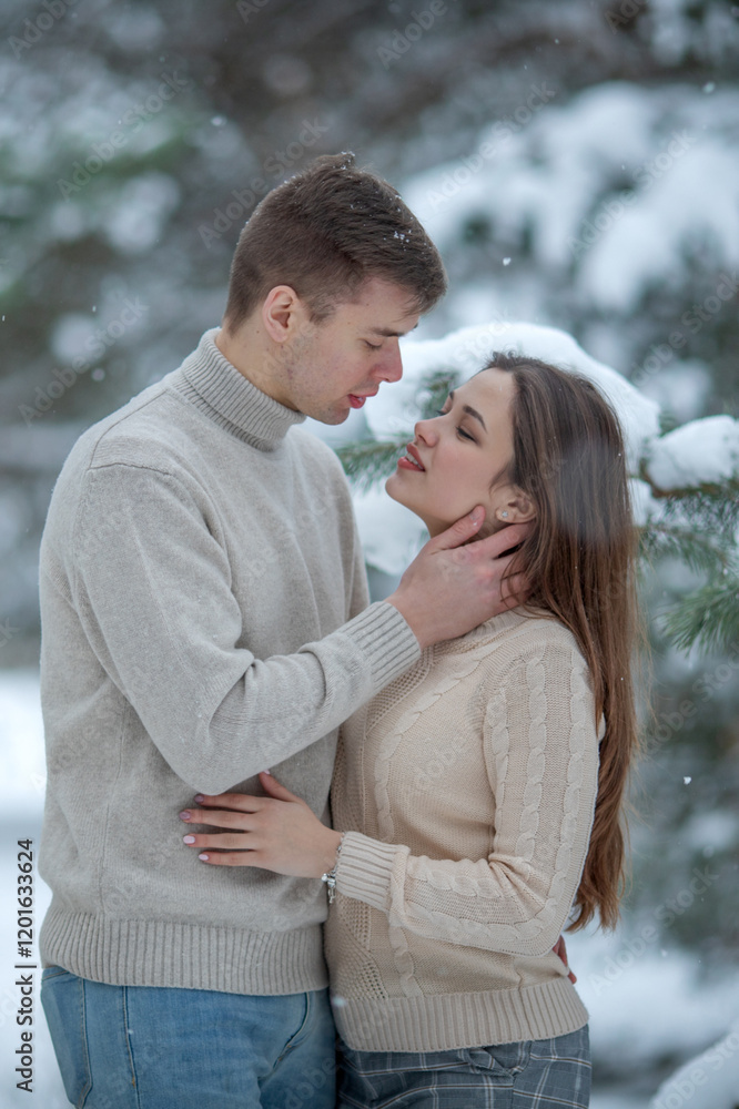 Fototapeta premium Young couple kissing in winter forest. Valentine's day date