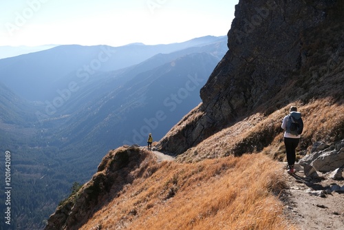 Scenery of autumn Tatras Mountains with very little silhouette of hiking person on trail. Czerwone Wierchy range from around Kasprowy Wierch Peak, Tatras Mountains, Poland.  