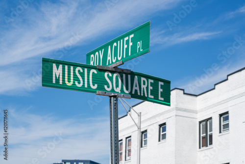 Two green street signs stand at a bright intersection in Nashville, Tennessee, indicating Roy Acuff Place and Music Square East on a sunny day.