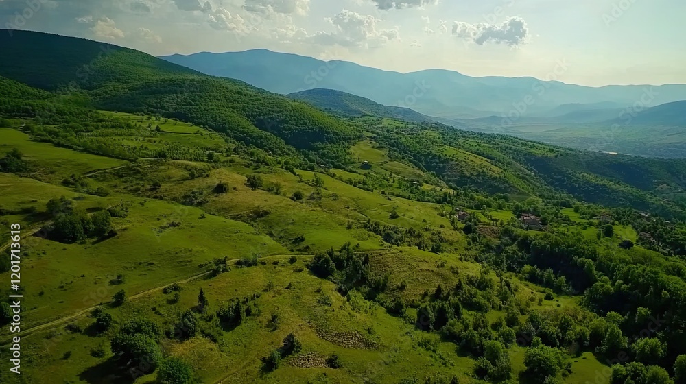 Obraz premium Aerial view of green hills, valley, and distant mountains. Background shows sunny sky, pastoral landscape. Use travel brochure, nature documentary