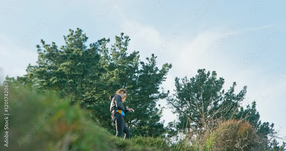 Woman in sportswear looking at her watch after climbing a steep slope Woman in sportswear looking at her watch after climbing a steep slope