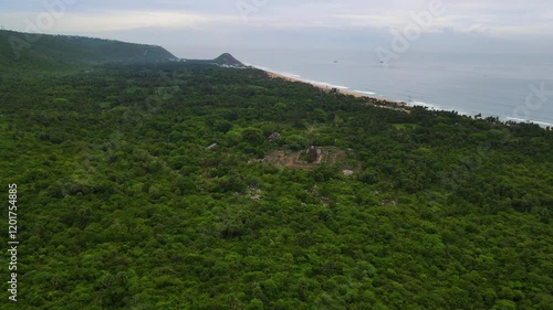 Aerial drone shot of a lush green forest nestled in the mountains, with the vast ocean stretching along the coastline in Vizag. photo