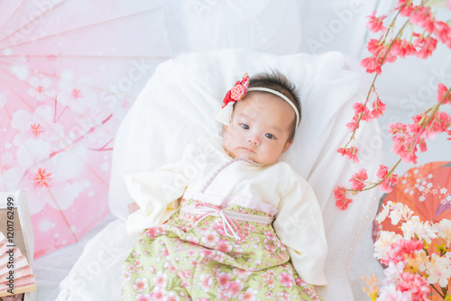 初節句のひな祭りで春の桜に囲まれて嬉しそうな赤い袴姿の可愛い女の子赤ちゃん