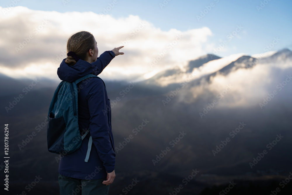 An unrecognizable traveler woman standing pointing the way on top of the mountain at the sunset. Female hiker showing finger at distance outdoors. Travel adventure hiking in the mountains. Copy space. An unrecognizable traveler woman standing pointing the way on top of the mountain at the sunset. Female hiker showing finger at distance outdoors. Travel adventure hiking in the mountains. Copy space.