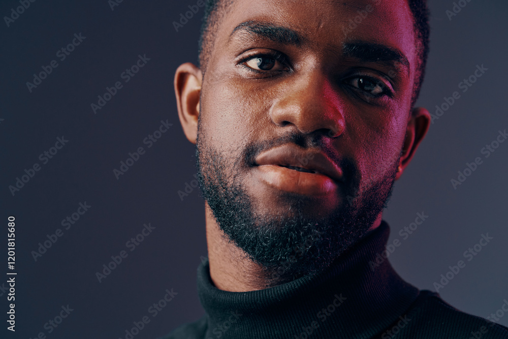 Portrait of a young Black man wearing a turtleneck sweater, showcasing confidence and thoughtfulness against a moody, colorful background Portrait of a young Black man wearing a turtleneck sweater, showcasing confidence and thoughtfulness against a moody, colorful background