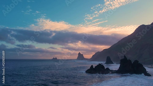 Ocean waves crash on rocks and spray in beautiful sunset light near Playa de Benijo beach in Tenerife, Canary Islands