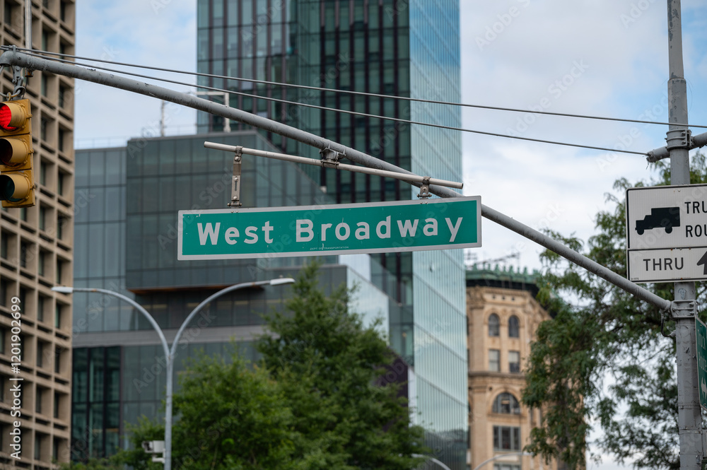 West Broadway street sign in a Manhattan featuring modern buildings and green trees on a clear day
