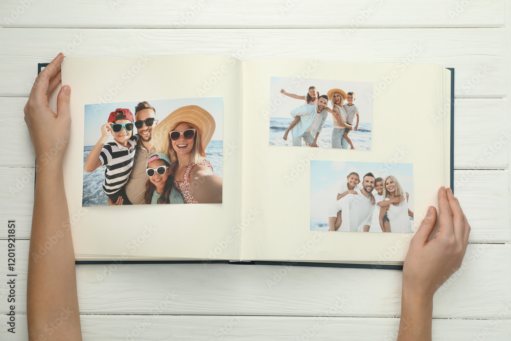 © New Africa - Woman with different photos in open photo album at white wooden table, top view