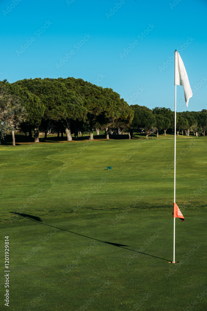 Obraz premium Golf course landscape with clear blue sky and lush green fairway in the afternoon in the Algarve, Portugal