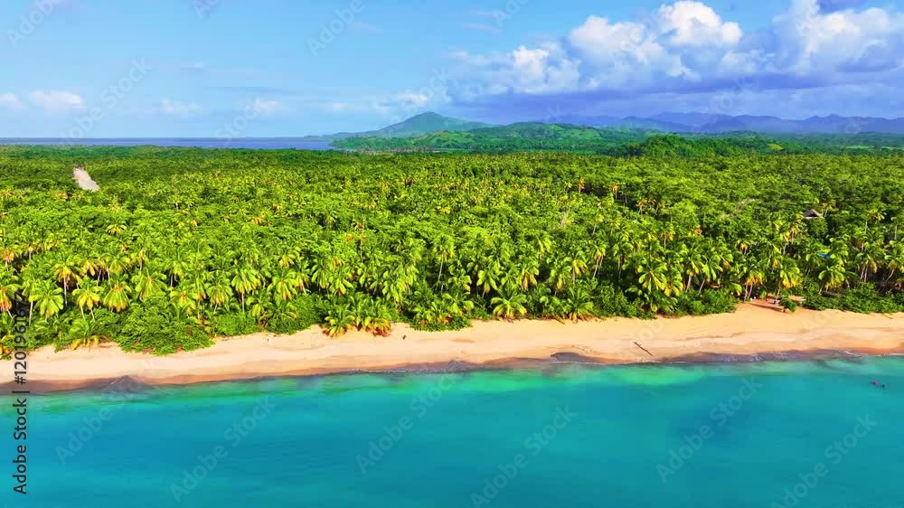 Aerial view of palm grove tropical mountainous peninsula. Best beaches in the world. Vivid sea concept of summer travel to tropical beach resort by calm blue sea. Mountain landscape with clouds.